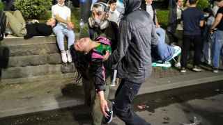 Демонстранты несут женщину, потерявшую сознание во время столкновений с полицией.